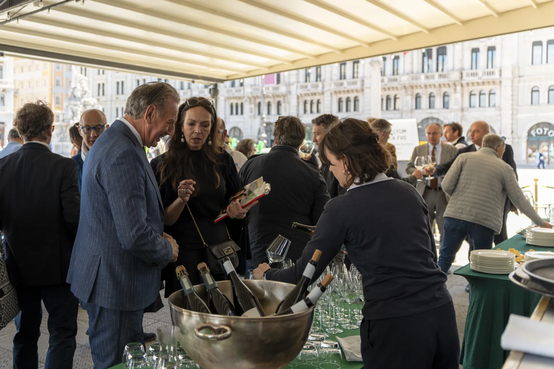 Il rinfresco di un evento aziendale in Piazza Unità d'Italia a Trieste, in una nostra fotografia: gli ospiti al banco dei vini sotto la tensostruttura